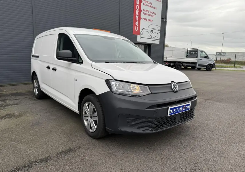 Volkswagen Caddy Maxi Cargo blanc candy vu en 3/4 avant droit avec pare-chocs noir mat et feux allumés.