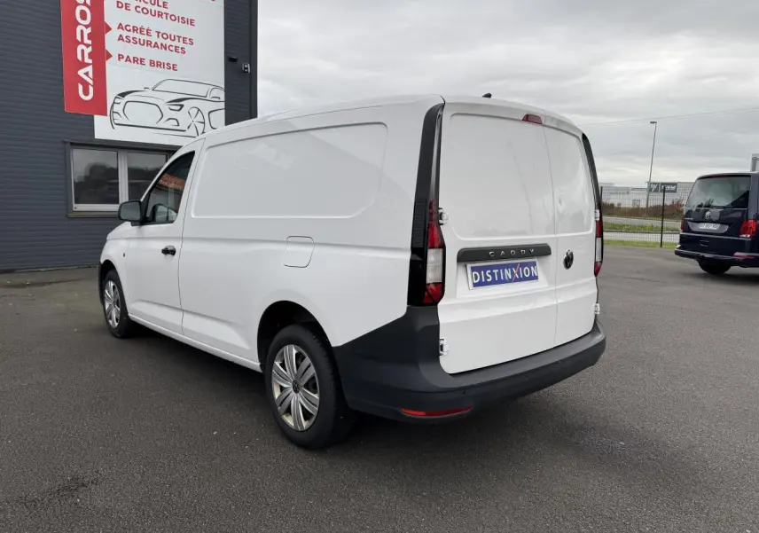 Vue 3/4 arrière droite d’un Volkswagen Caddy Maxi Cargo blanc Candy avec pare-chocs noirs et porte coulissante visible.