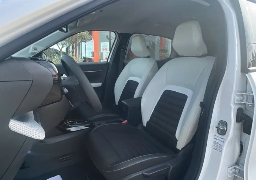 Vue intérieure côté conducteur du Citroën C3 Aircross blanc banquise, sièges tissu bicolores avec accoudoir central.