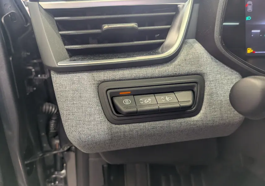 Détail du tableau de bord côté gauche de la Renault Clio V 2025, avec tissu gris schiste et commandes d’éclairage.