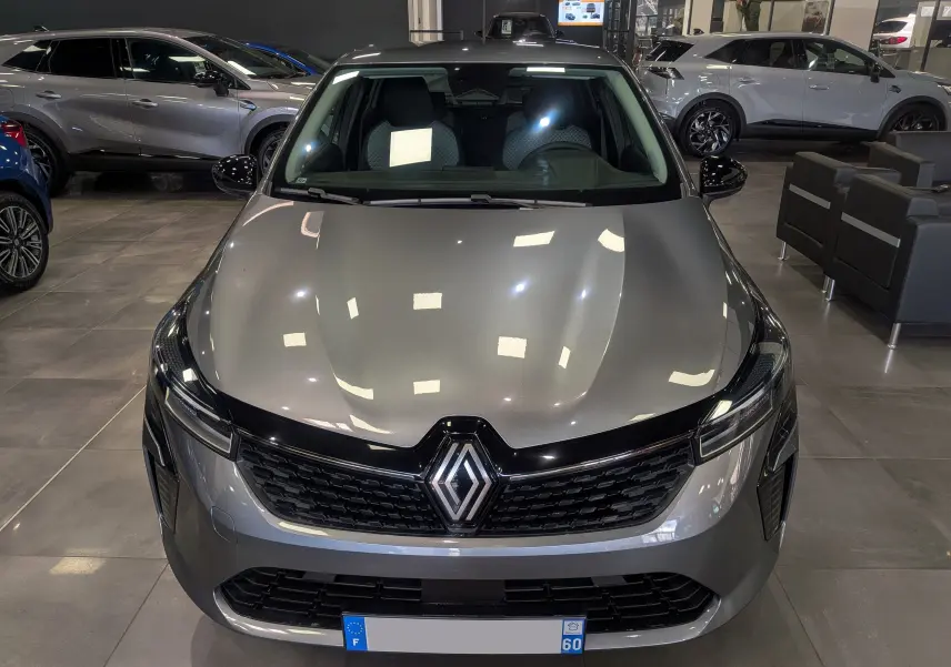 Vue avant d'une Renault Clio V gris schiste, mettant en valeur sa calandre noire et ses phares fins en intérieur showroom.