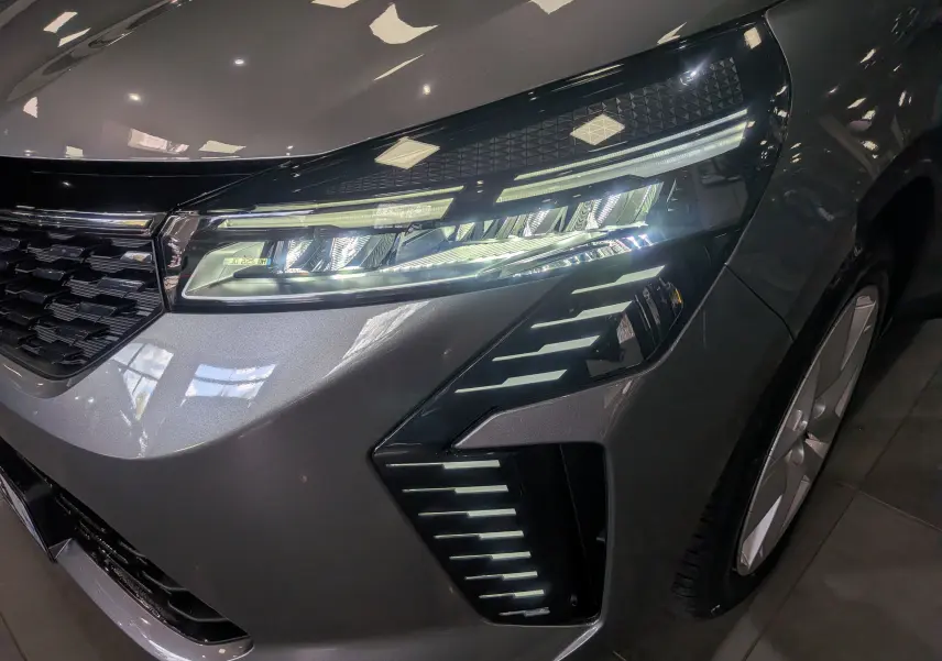 Gros plan sur l'avant droit gris schiste de la Renault Clio V 2025, mettant en valeur ses phares LED et la calandre noire.