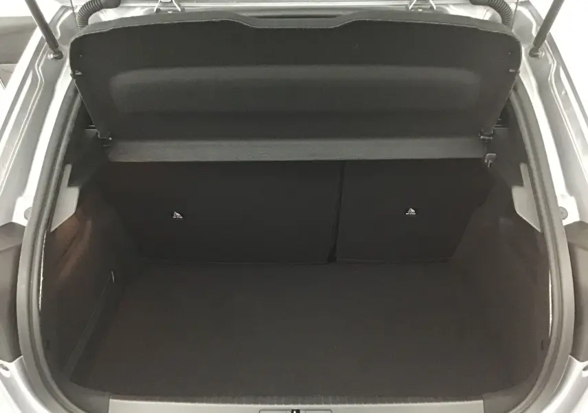 Coffre ouvert vu de dessus d'une Peugeot 208 gris Artense, montrant un espace de chargement propre et vide.