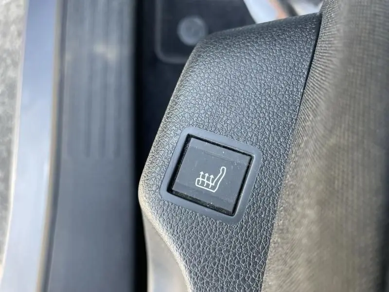 Bouton de chauffage de siège en gros plan sur la console intérieure d'un Citroën Berlingo gris métal 2018.