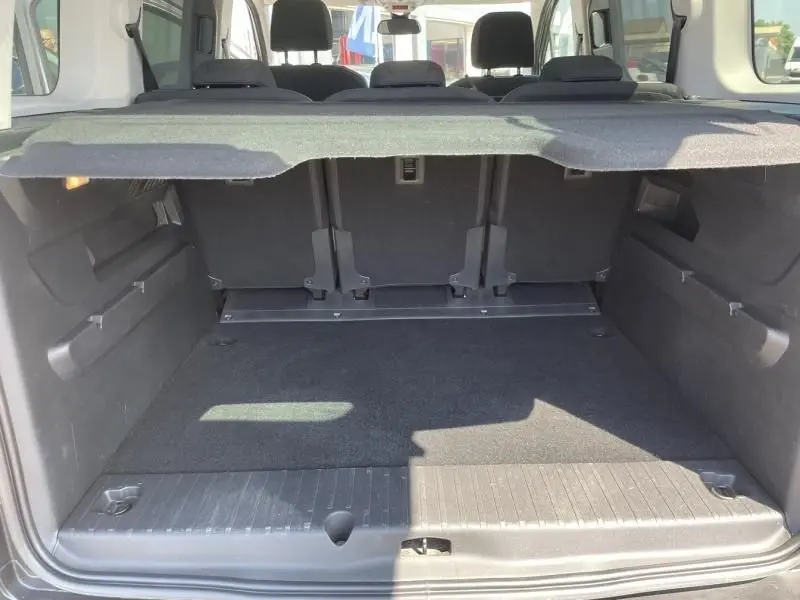 Vue du coffre ouvert du Citroën Berlingo gris métal 2018, montrant l'espace de chargement et les sièges arrière.
