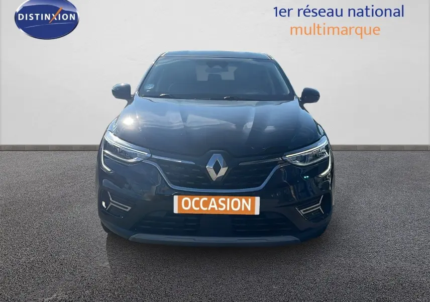 Vue frontale d'un Renault Arkana noir métal 2023 avec calandre distinctive et phares LED allumés.