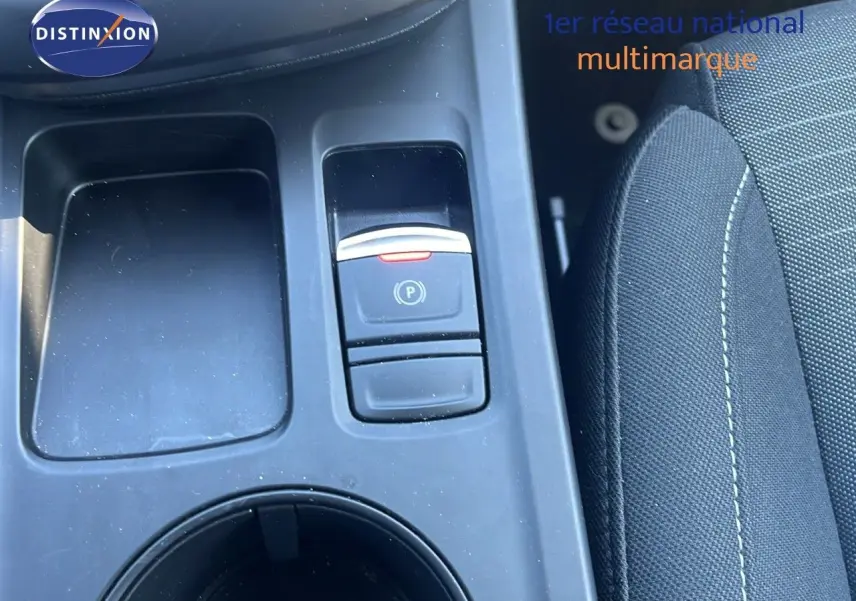 Gros plan sur la console centrale noire du Renault Arkana 2023, avec bouton de frein à main électronique et siège tissu gris.