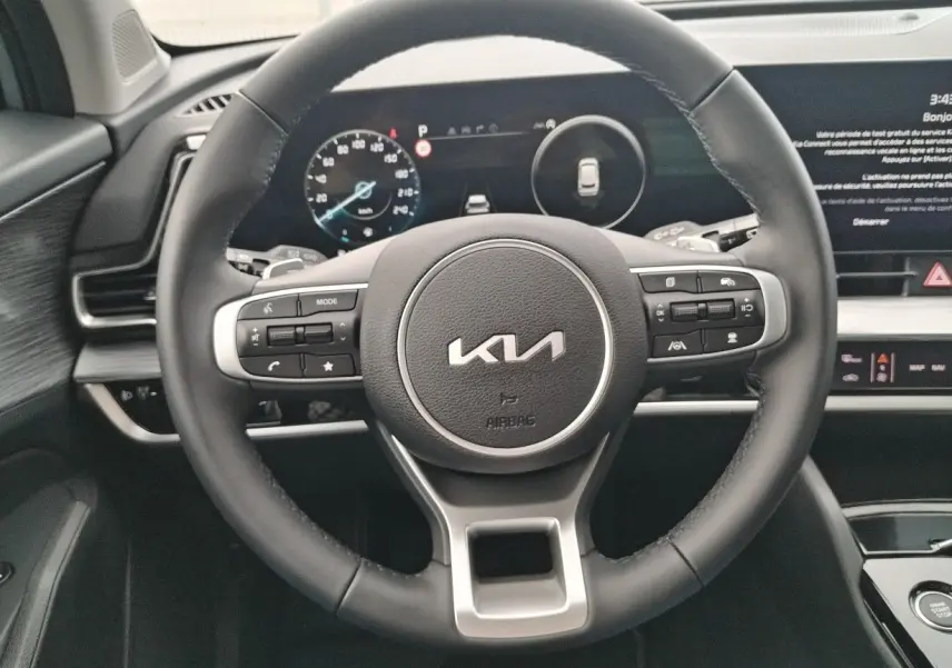 Vue rapprochée du volant noir du Kia Sportage 2025 avec commandes intégrées et tableau de bord numérique.