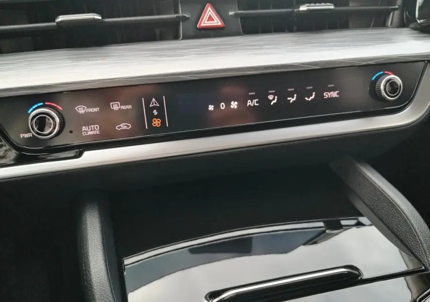 Vue rapprochée de la console centrale du Kia Sportage 2025, avec commandes de climatisation et finition bois gris perle.