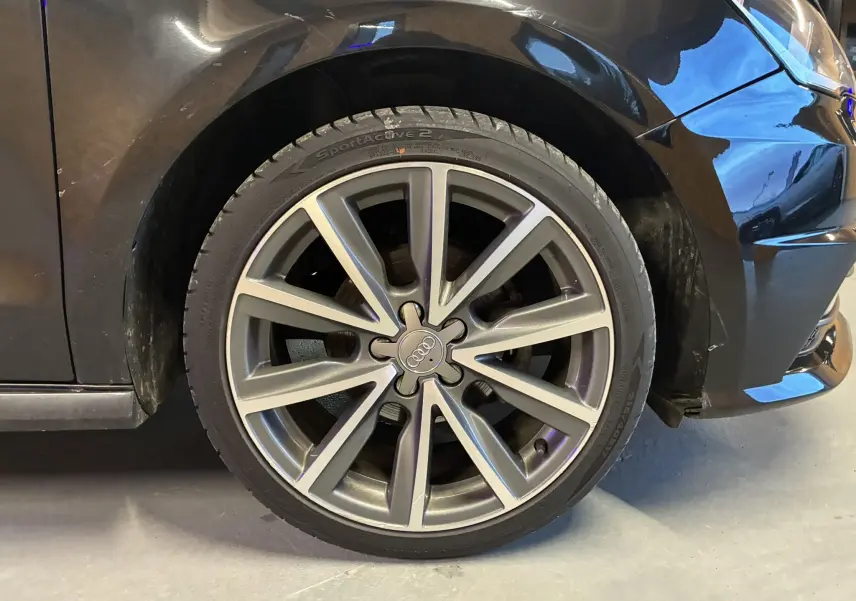 Gros plan sur la roue avant droite d'une Audi A1 noire de 2016 avec jante alliage 17 pouces S-Line.