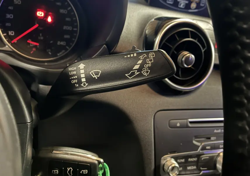 Gros plan sur la commande d’essuie-glace à gauche du volant dans l’habitacle noir d’une Audi A1 2016 S-Line.