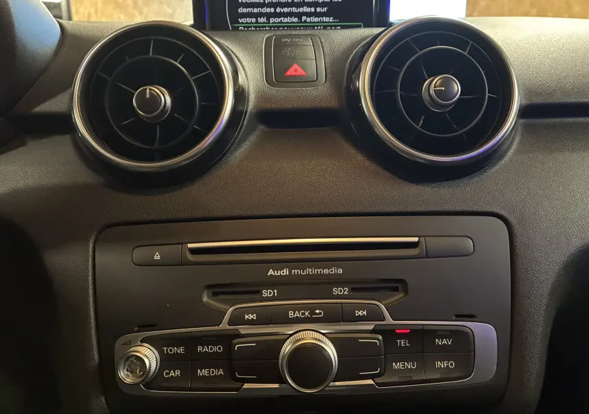 Vue rapprochée du tableau de bord noir de l'Audi A1 2016, mettant en valeur les aérateurs ronds et la console multimédia.