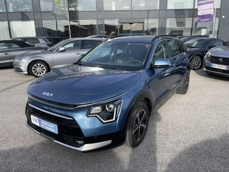 KIA Niro 2024 bleu métal en vue 3/4 avant droit, avec signature lumineuse distinctive et jantes noires.