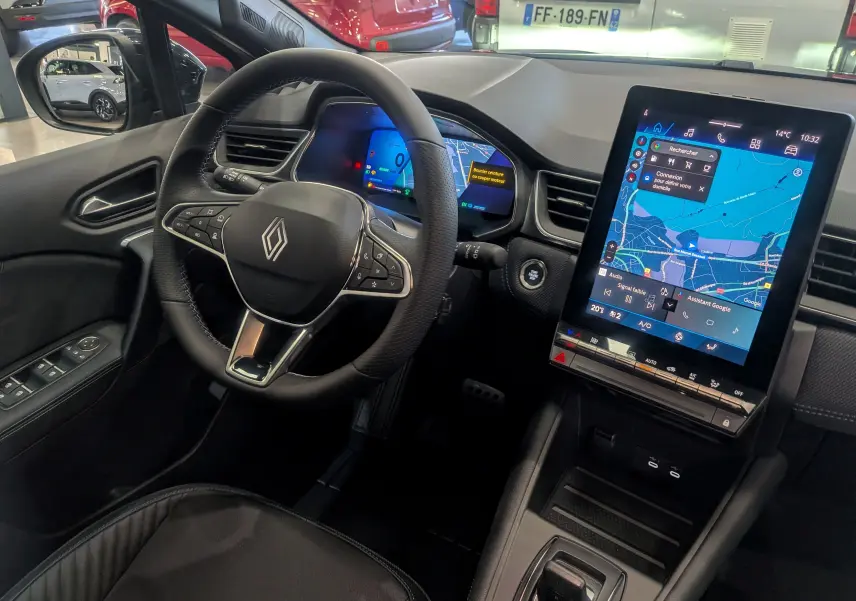 Vue intérieure côté conducteur de la Renault Symbioz E-TECH hybride, avec tableau de bord numérique et écran tactile central.