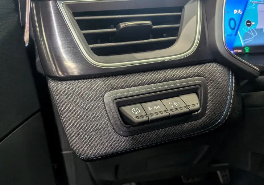 Gros plan sur la console côté conducteur du Renault Symbioz gris Cassiopé, avec boutons E-SAVE et réglage phares.