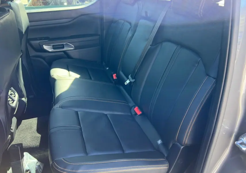 Vue intérieure côté arrière droit du Ford Ranger 2025 gris carbone, montrant les sièges en cuir noir avec surpiqûres contrastantes.