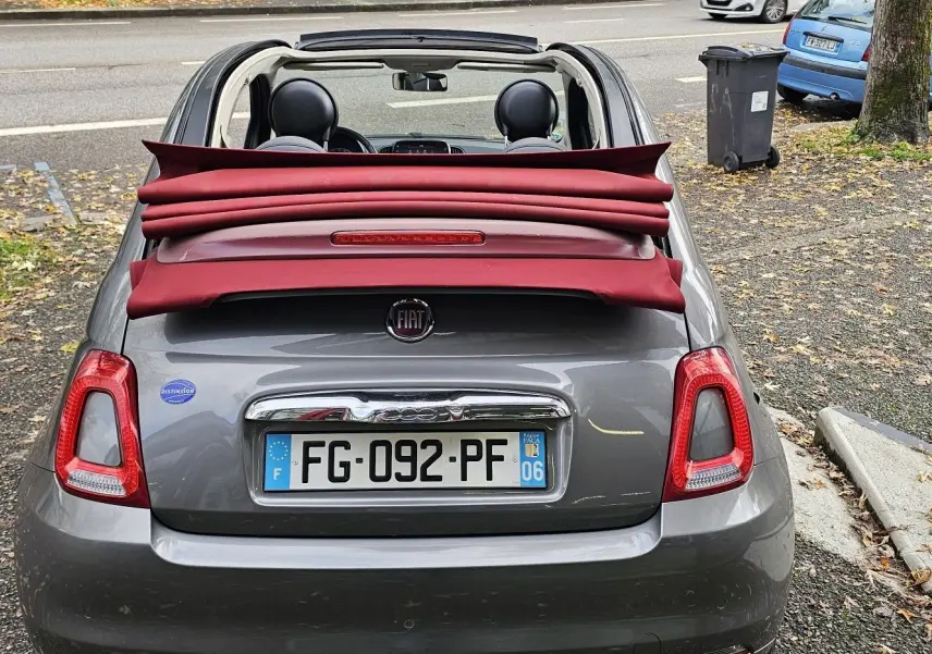 Gros plan sur le levier de vitesses manuel noir dans l'habitacle d'une Fiat 500C grise, avec commandes de climatisation visibles.