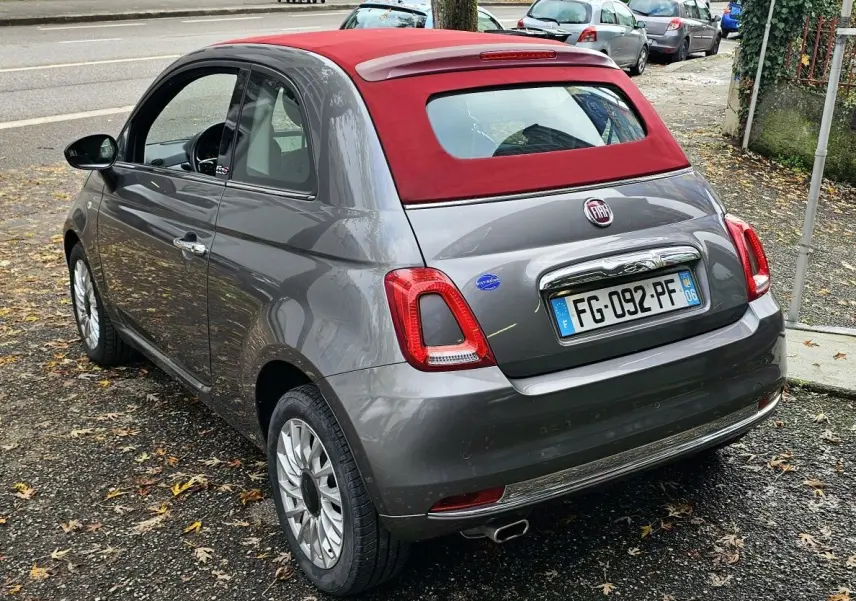 Fiat 500C gris métallisé vue 3/4 avant droit avec toit rouge et jantes alliage sur fond neutre.