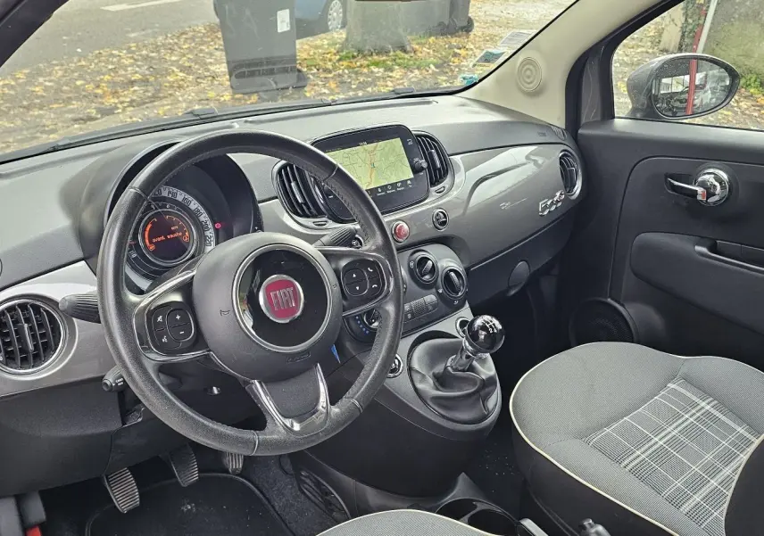 Fiat 500C grise électroclash vue 3/4 arrière côté droit avec toit rouge cabriolet fermé sur parking.