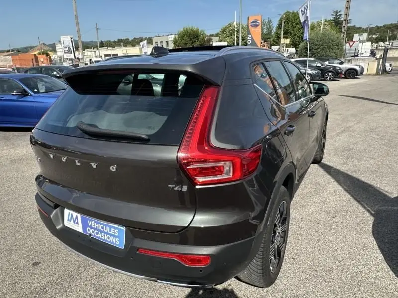 Vue 3/4 arrière droite d'un Volvo XC40 T4 gris foncé métal avec feux arrière en L et toit panoramique visible.