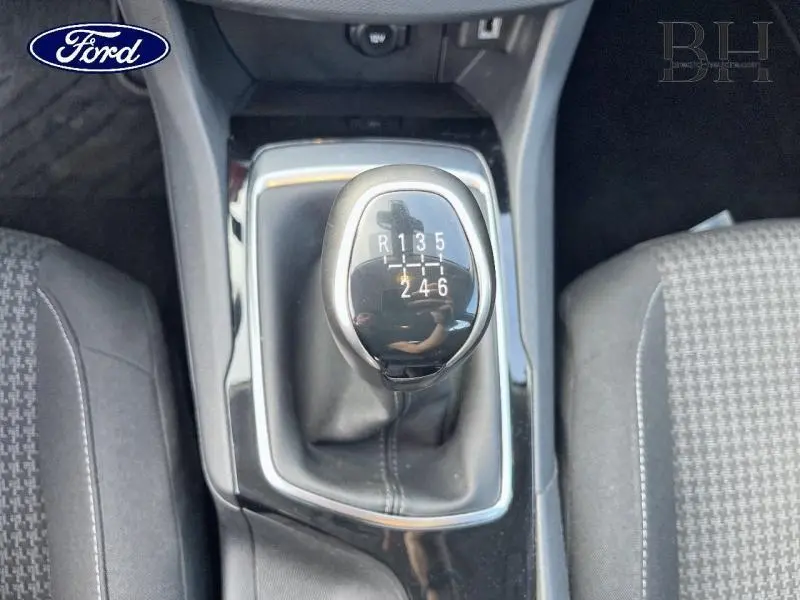 Le levier de vitesses manuel en gros plan, entouré des sièges avant gris à motif tissu.