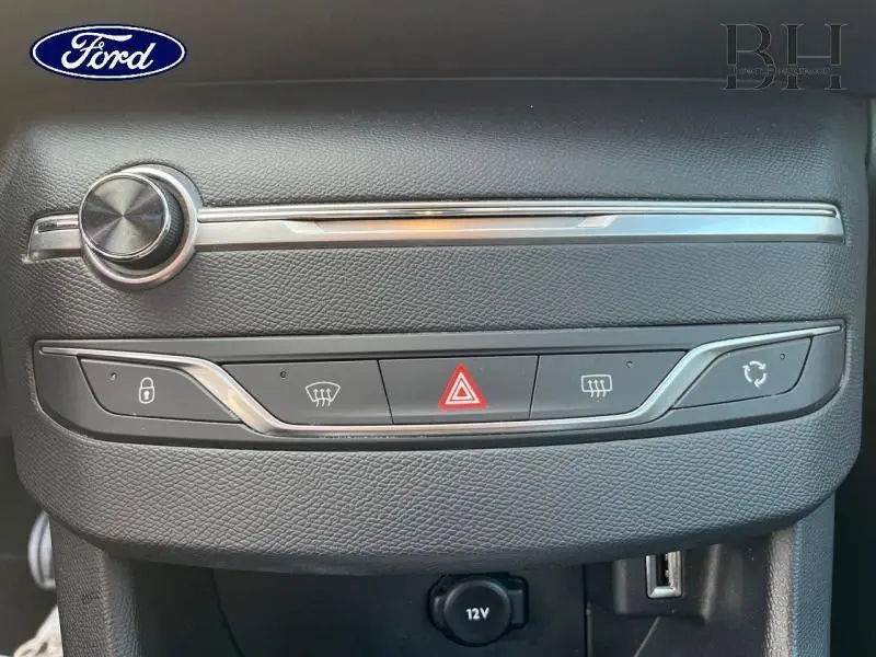 Détail du tableau de bord noir avec commandes de verrouillage, dégivrage, et bouton de warning sur Peugeot 308 SW gris Artense.