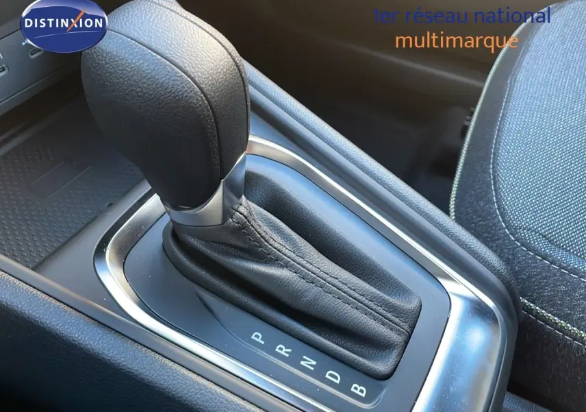 Le levier de vitesses automatique en cuir noir du Renault Captur E-Tech Hybrid 2025, avec console et siège tissu gris.