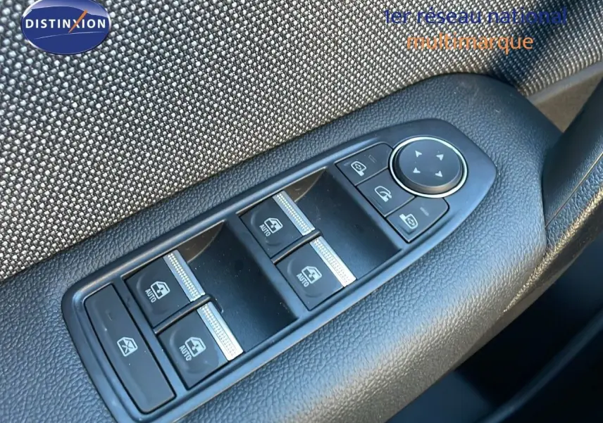 Vue rapprochée des commandes des vitres électriques sur la portière côté gauche du Renault Captur bleu Iron Metal toit noir.