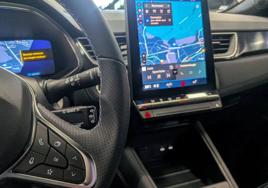 Vue intérieure rapprochée du volant en cuir noir et de l’écran tactile central affichant la navigation du Renault Symbioz E-Tech.