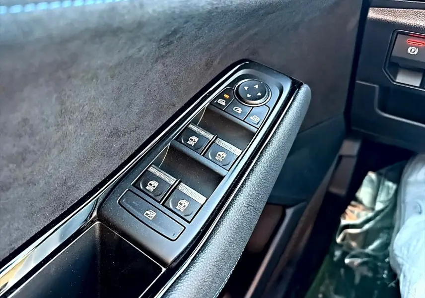 Gros plan sur la commande des vitres électriques côté conducteur du Renault Austral noir, avec revêtement en alcantara.