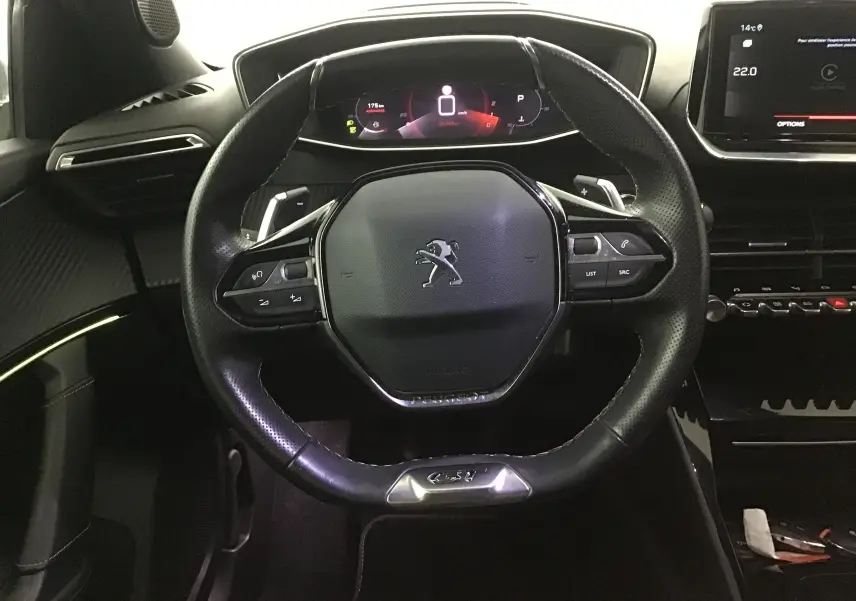 Vue rapprochée du volant cuir noir et du tableau de bord numérique du Peugeot 2008 GT blanc nacré de 2021.