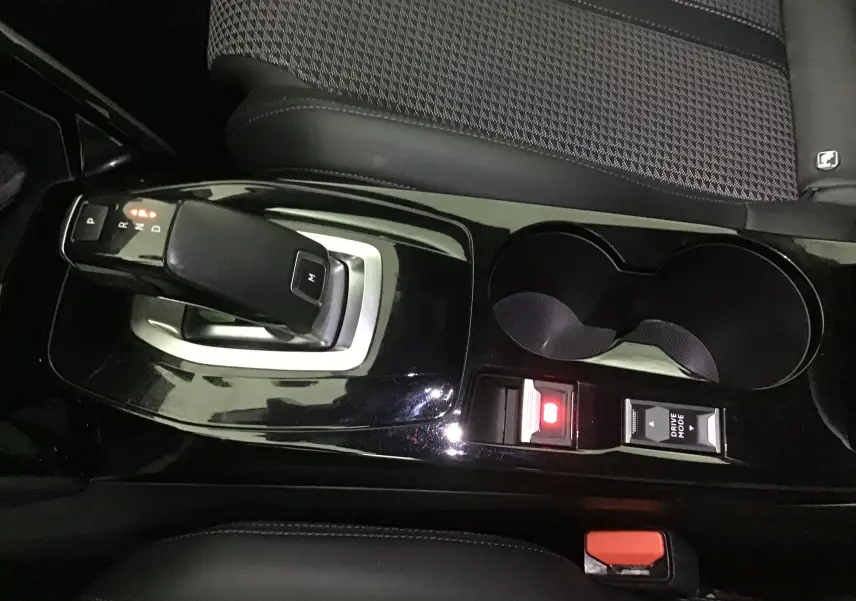 Vue rapprochée de la console centrale noire brillante du Peugeot 2008 GT 2021 avec levier de vitesse automatique et porte-gobelets.