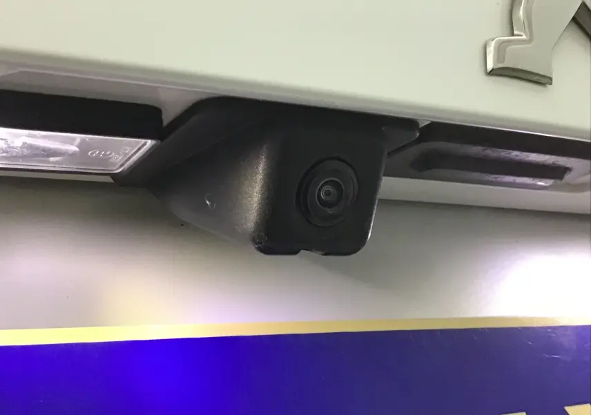 Gros plan sur la caméra de recul noire intégrée au hayon blanc nacré du Peugeot 2008 GT 2021.