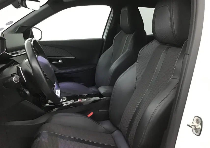 Vue intérieure côté conducteur du Peugeot 2008 blanc nacré, mettant en valeur les sièges sport en cuir noir et le volant multifonction.