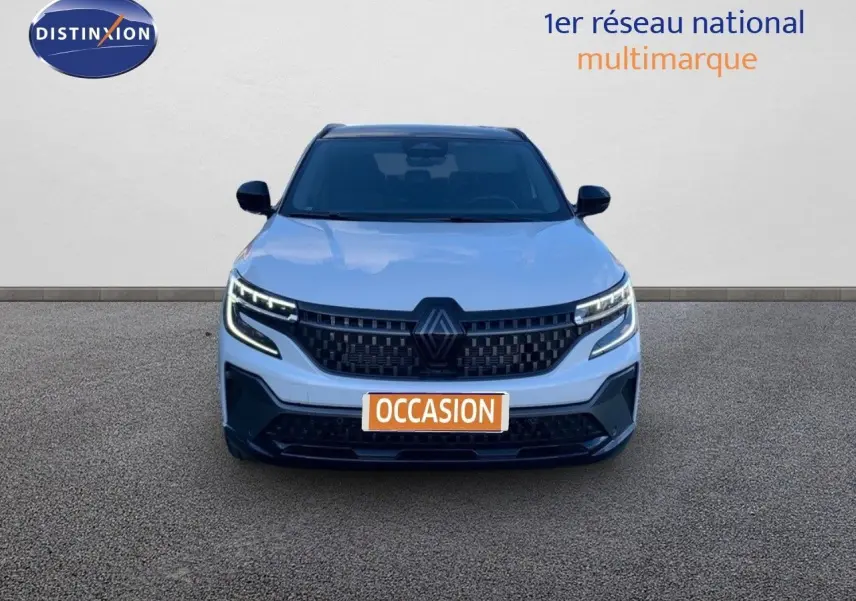 Vue avant d'un Renault Austral blanc métal avec toit noir, phares LED allumés et calandre noire distinctive.