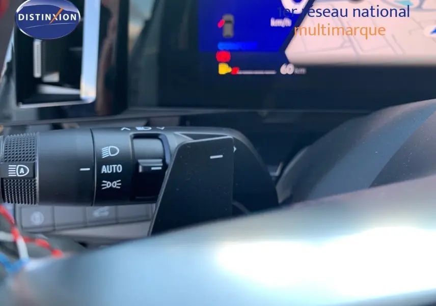 Gros plan sur la commande des phares et l'écran digital du tableau de bord du Renault Austral blanc métal 2024.