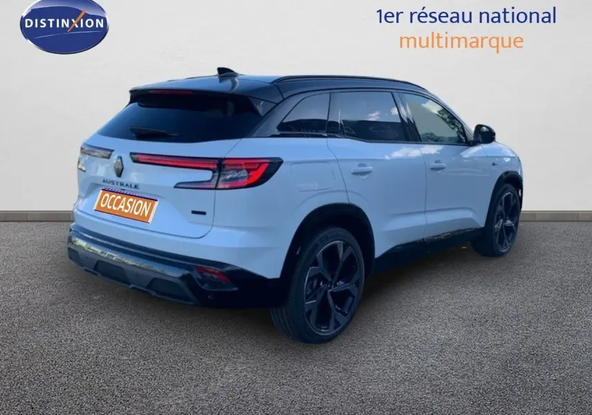 Vue 3/4 arrière droite d’un Renault Austral blanc métal avec toit noir et jantes noires sur fond neutre.