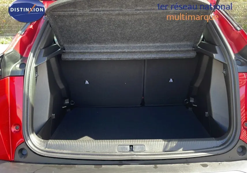 Coffre ouvert vu de l'arrière d'une Peugeot 2008 rouge Elixir Metal, montrant un espace de chargement vide et propre.