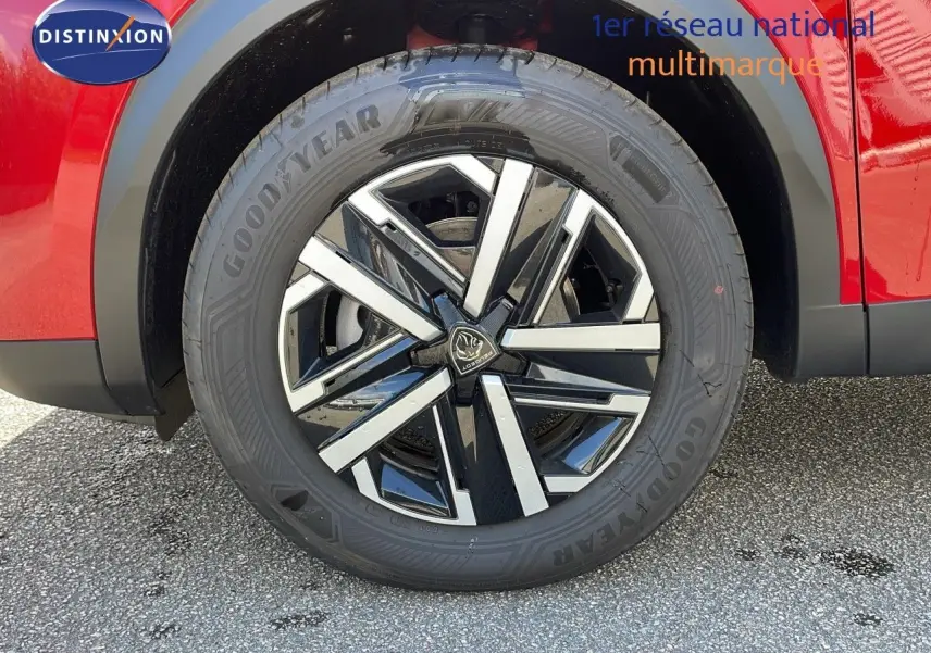 Gros plan sur la roue avant droite d'un Peugeot 2008 rouge Elixir Metal avec jante alliage bicolore moderne.