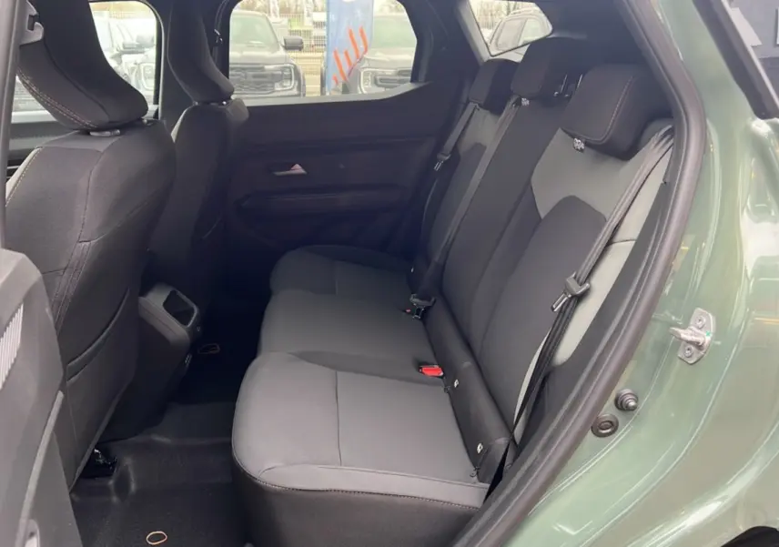 Vue côté droit sur l'intérieur arrière du Dacia Duster 2025 kaki lichen, montrant les sièges en tissu noir et gris.