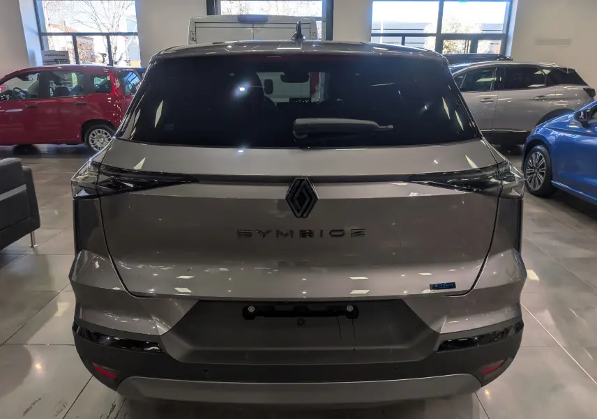 Vue arrière d'une Renault Symbioz gris Cassiopé en showroom, avec logo central et feux arrière étirés noirs.
