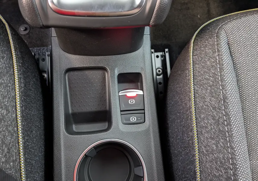Gros plan sur la console centrale du Renault Captur 2025, montrant frein de parking électrique et sellerie tissu gris avec surpiqûres jaunes.