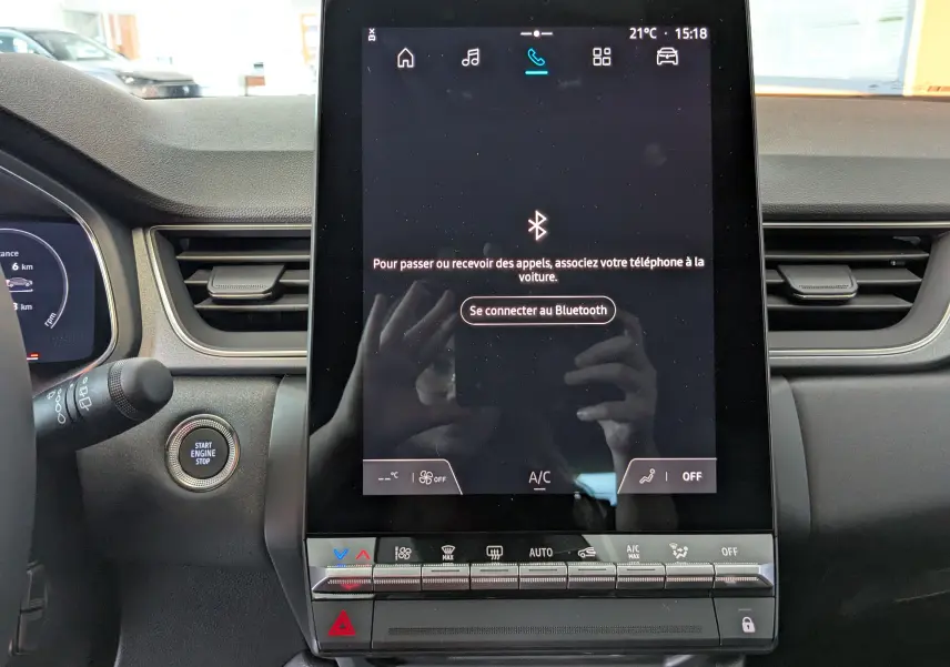 Écran tactile central du tableau de bord du Renault Captur 2025 gris zinc, avec commandes climatisation et bouton start/stop visibles.