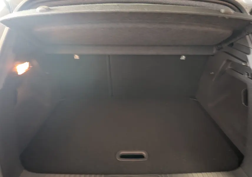 Coffre spacieux et éclairé du Renault Captur 2025 gris zinc, vue intérieure arrière avec cache-bagages relevé.