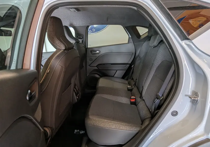 Vue intérieure côté droit des sièges arrière en tissu gris du Renault Captur 2025 gris zinc avec porte ouverte.
