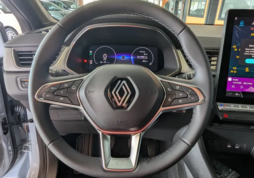 Vue centrée sur le volant noir du Renault Captur 2025 avec tableau de bord numérique et écran tactile latéral.