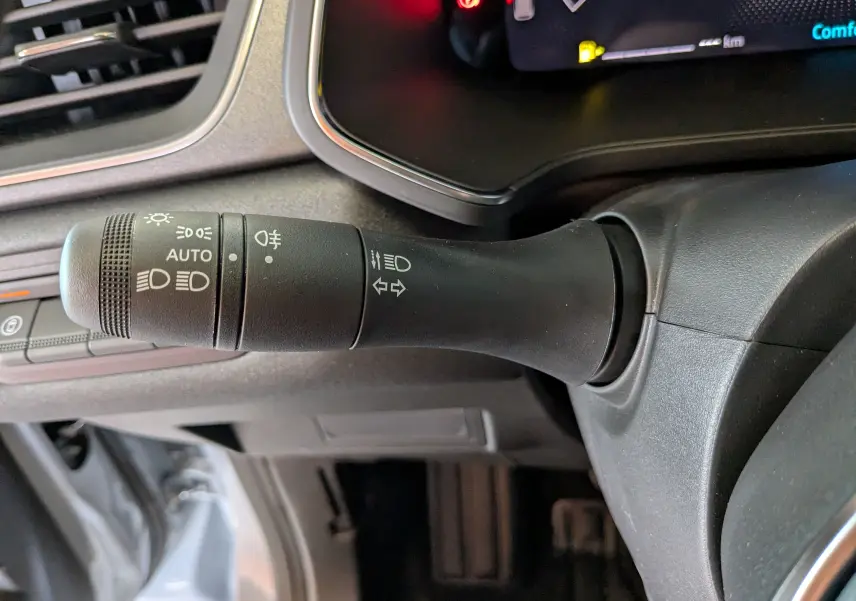 Gros plan sur la commande des phares et clignotants à gauche du volant dans un Renault Captur gris zinc 2025.