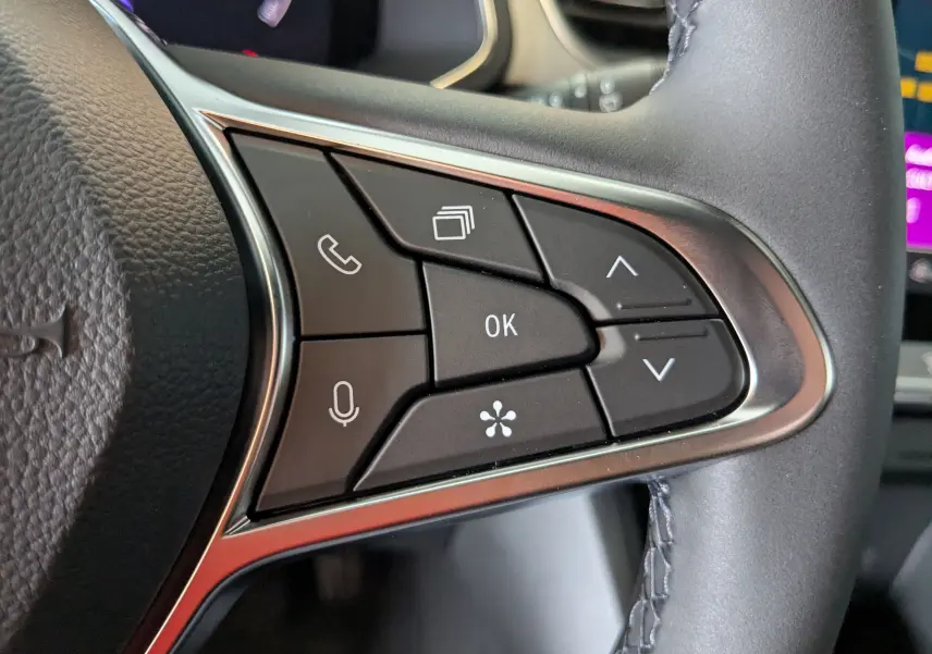 Gros plan sur les commandes multifonctions noires du volant côté droit du Renault Captur gris zinc 2025.