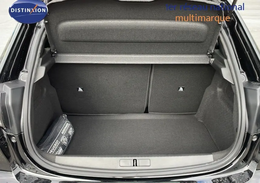 Coffre ouvert d'une Peugeot 208 noir perla metal, montrant un espace de rangement propre et un kit d'assistance sur le côté gauche.