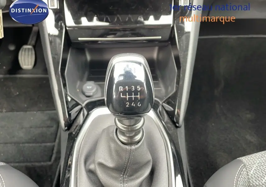 Le levier de vitesses manuel noir de la Peugeot 208 2024, vu de dessus dans l'habitacle sombre.